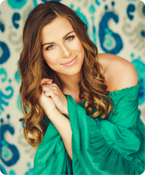 Portrait of a smiling woman standing in front of a vibrant colorful background.